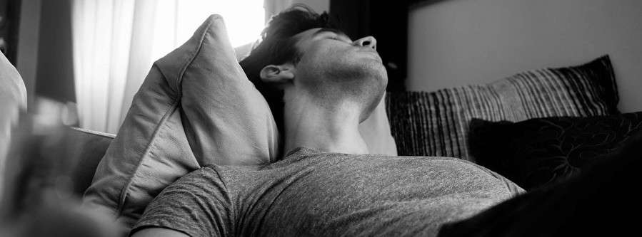 grayscale photo of man laying on bed